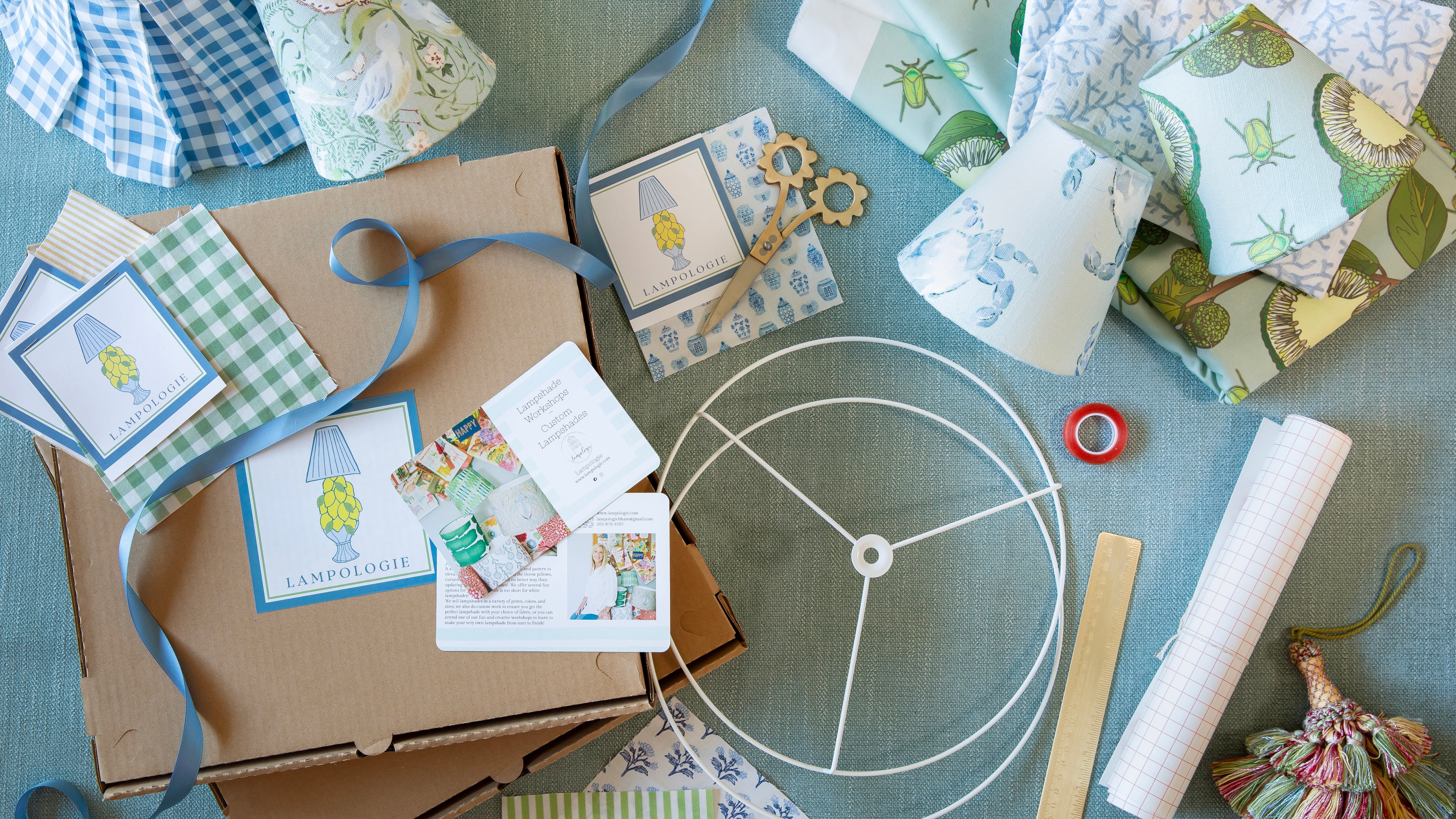 Lampshade kit materials including instruction cards, ribbons, and fabric on a blue surface.