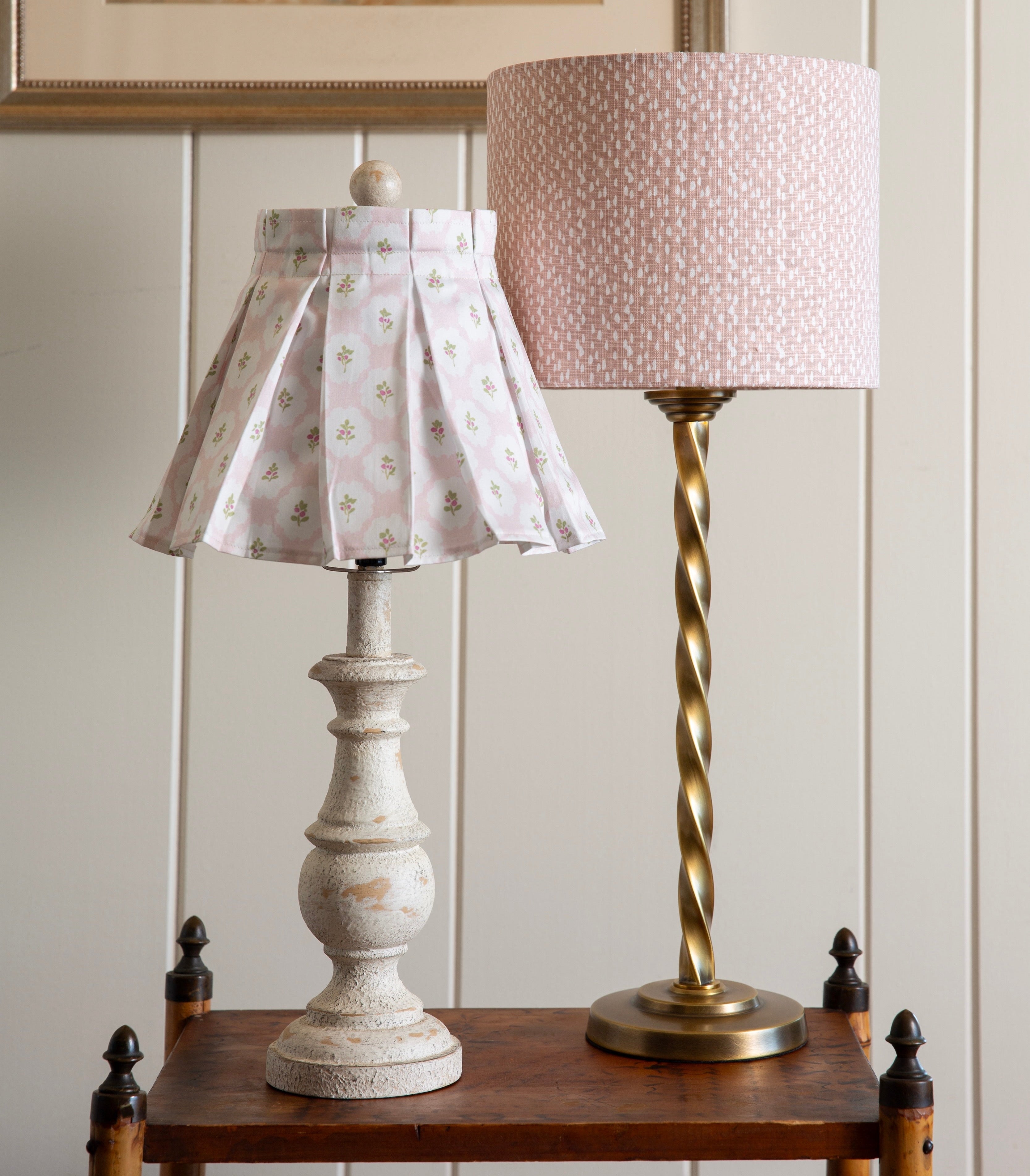 Two lamps with pink made to order lampshades on a wooden table with a neutral background